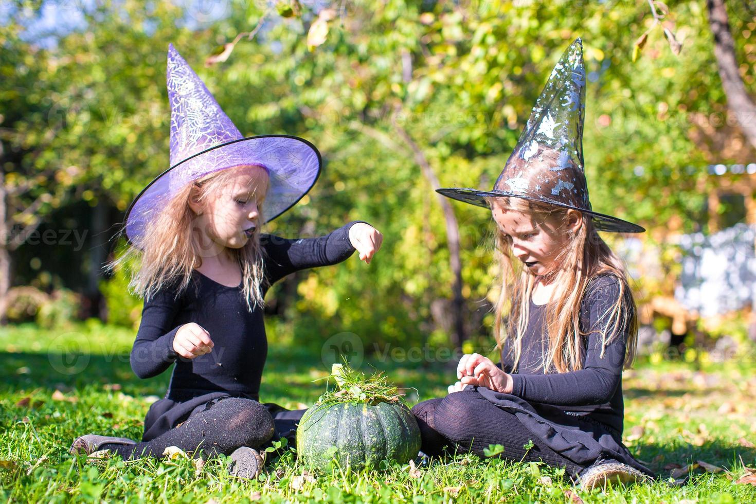 Adorable little girls in witch costume casting a spell on Halloween photo