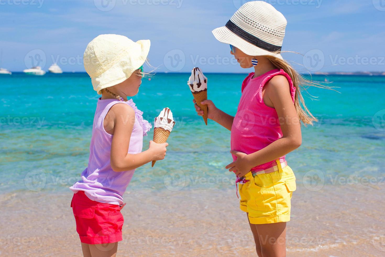 Little adorable girls eating ice cream on tropical beach photo