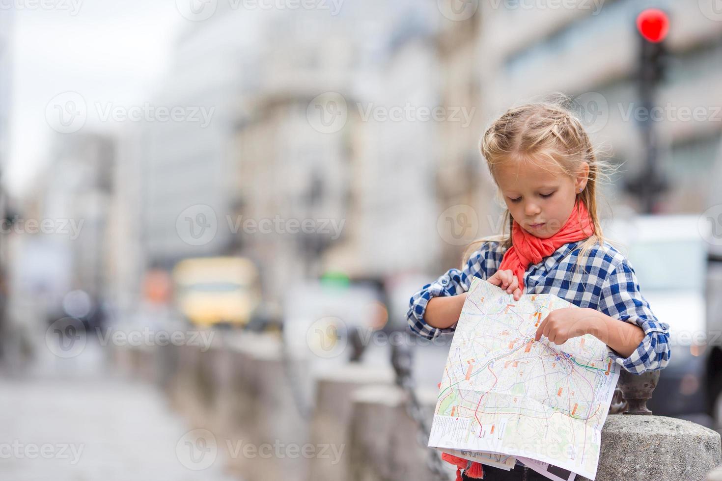 Adorable little girl with map of european city outdoors photo