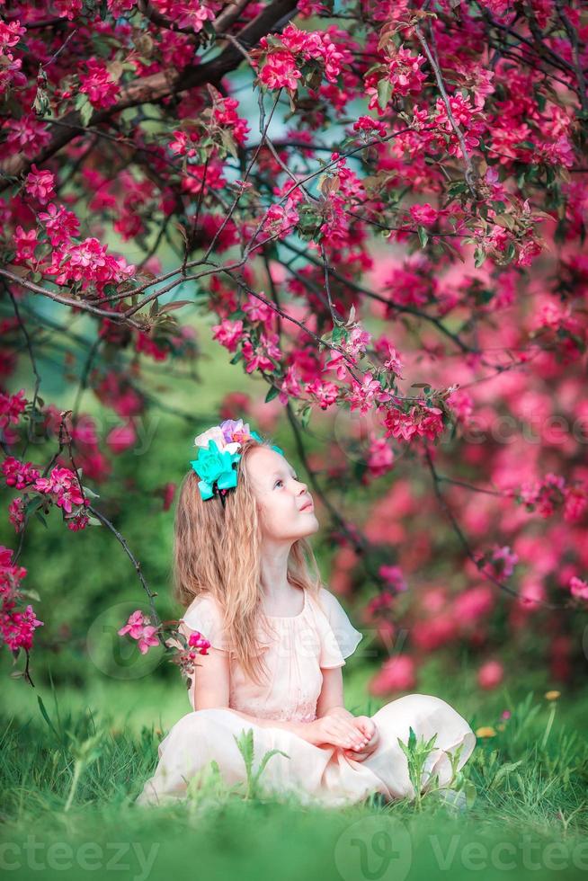 Adorable little girl in beautiful blooming apple garden outdoors photo