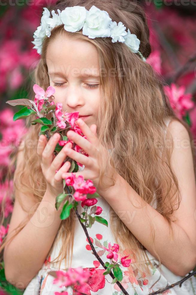 adorable niñita disfrutando del olor en un florido jardín primaveral foto