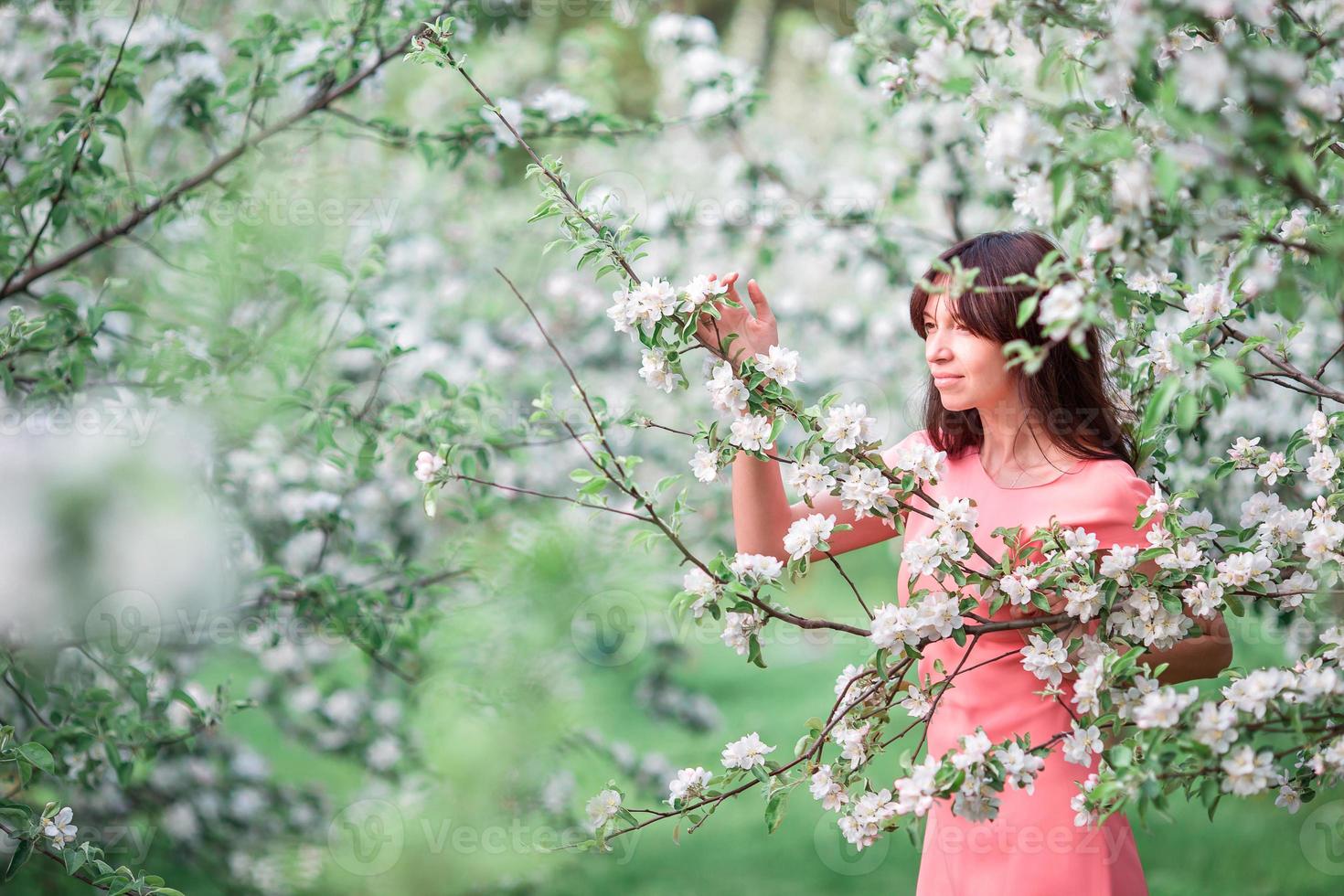 hermosa chica disfrutando del olor en el jardín de cerezos de primavera foto