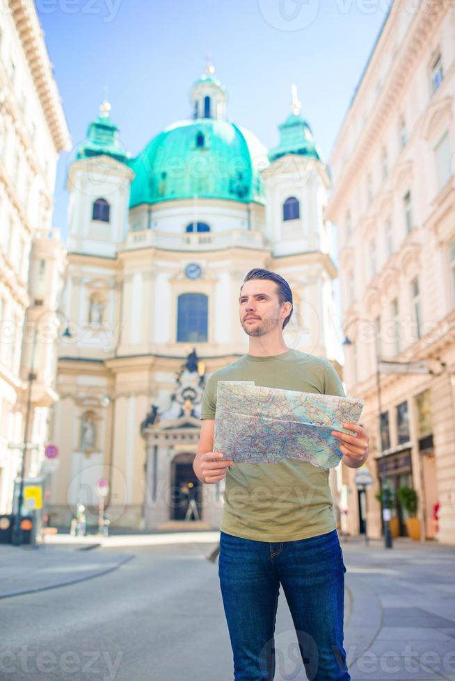 Man tourist with a city map and backpack in Europe street. Caucasian boy looking with map of European city. photo