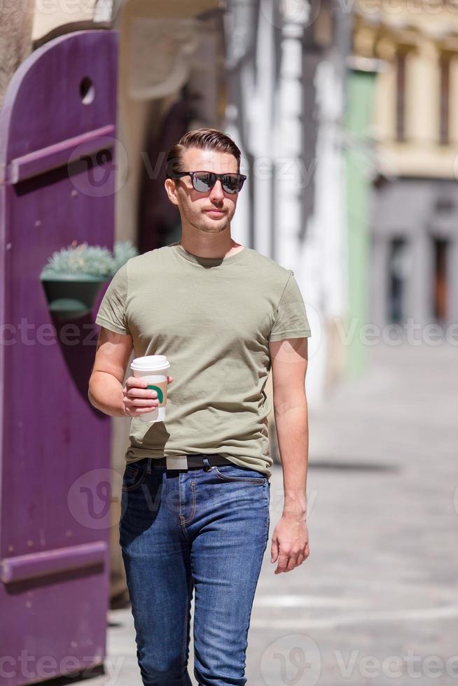 feliz joven hombre urbano bebiendo café en la ciudad europea al aire libre foto