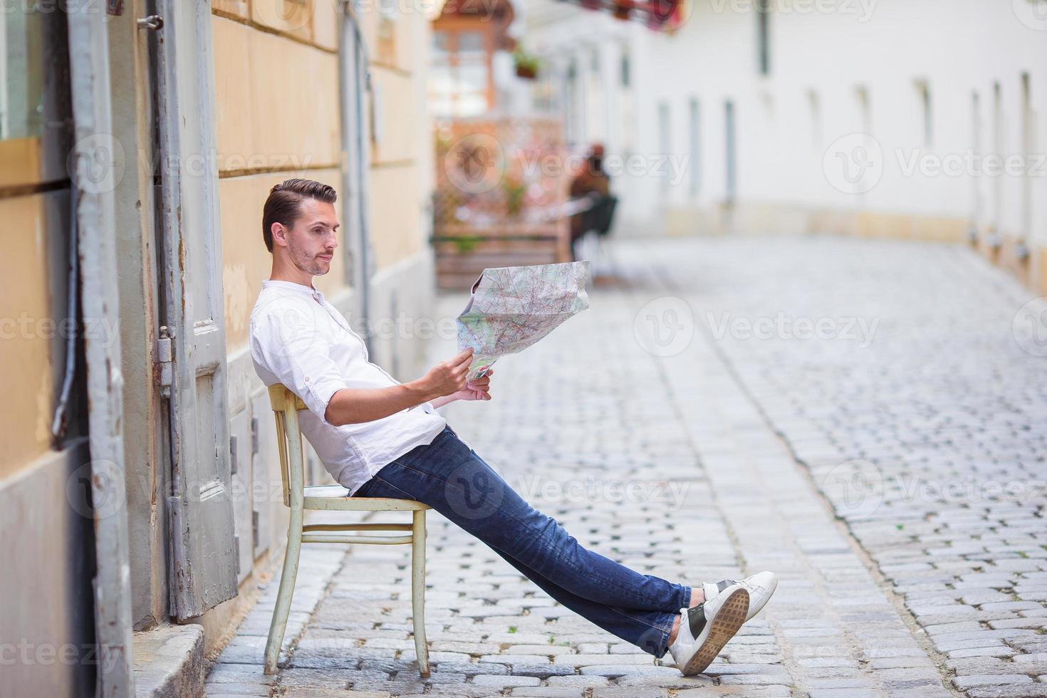 Man tourist with a city map and backpack in Europe street. Caucasian boy looking with map of European city. photo