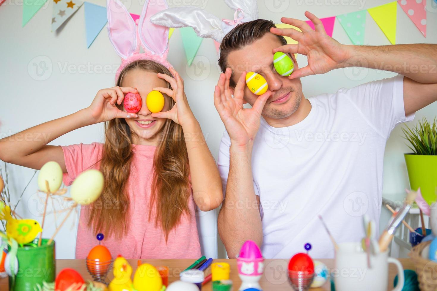 Father and his little daughter painting eggs. Happy family preparing for Easter. photo