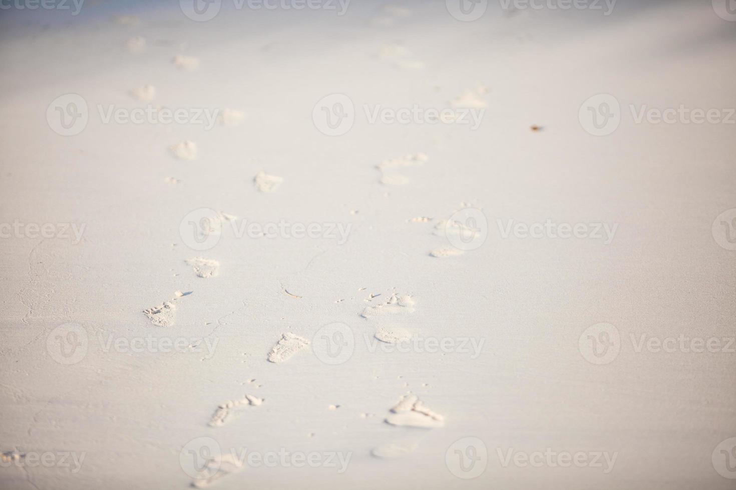 Human footprints on the white sandy beach photo