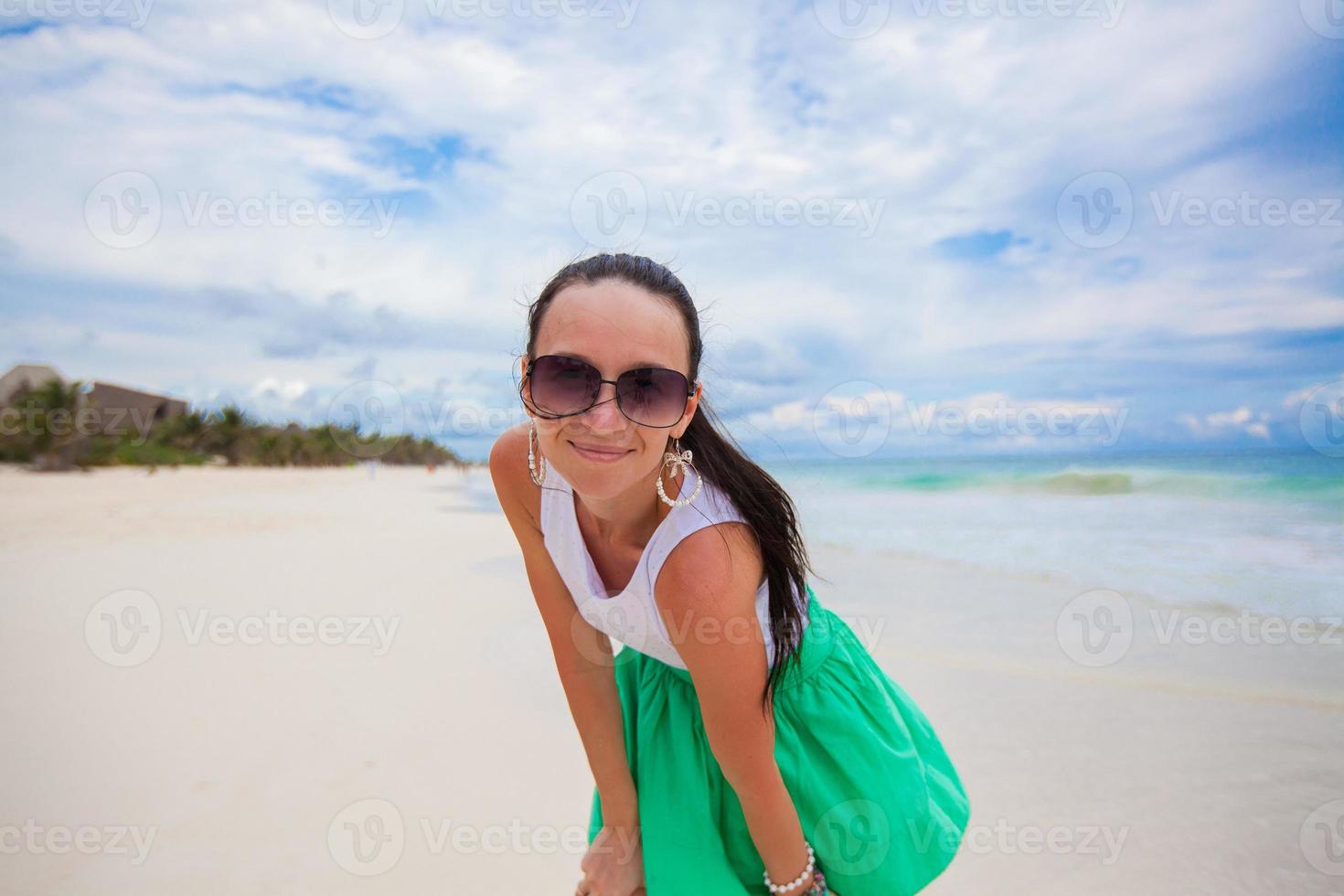 Close-up of young woman on the white exotic beach looking at camera photo