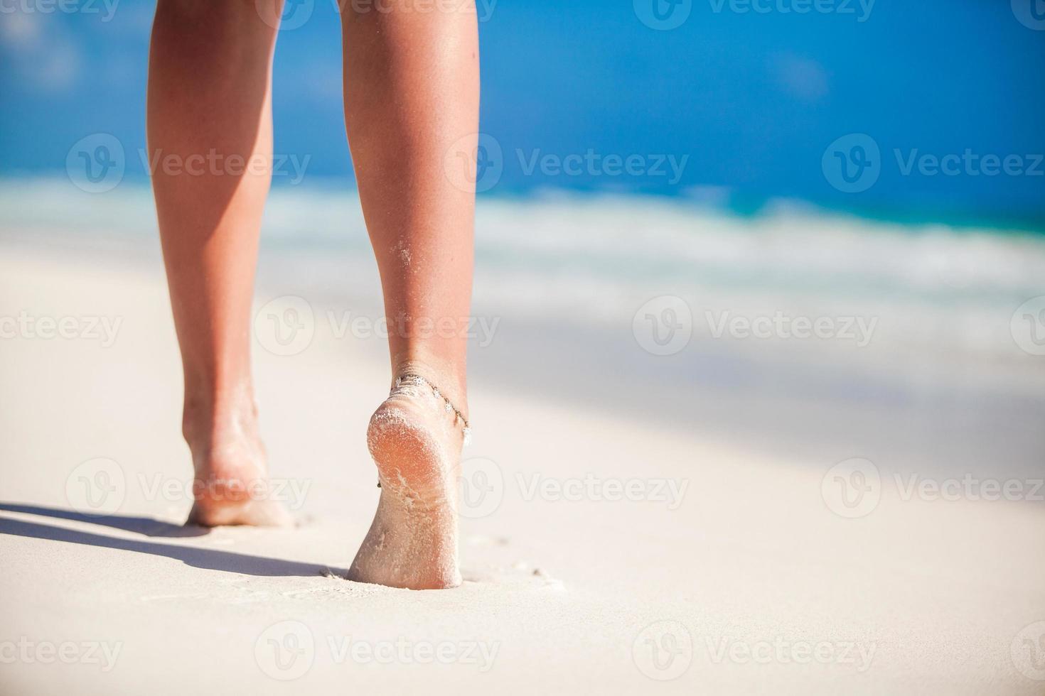 Women's beautiful smooth legs on white sand beach photo