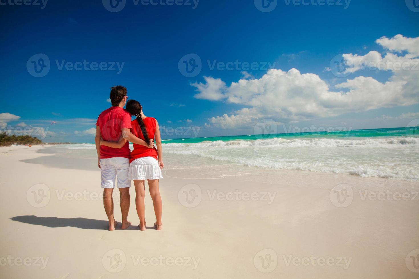 Young romantic couple walking on exotic beach in sunny day photo