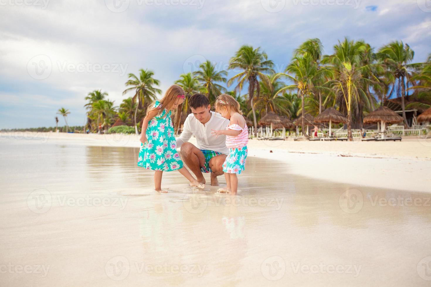 Father and his adorable little daughters playing on the beach photo