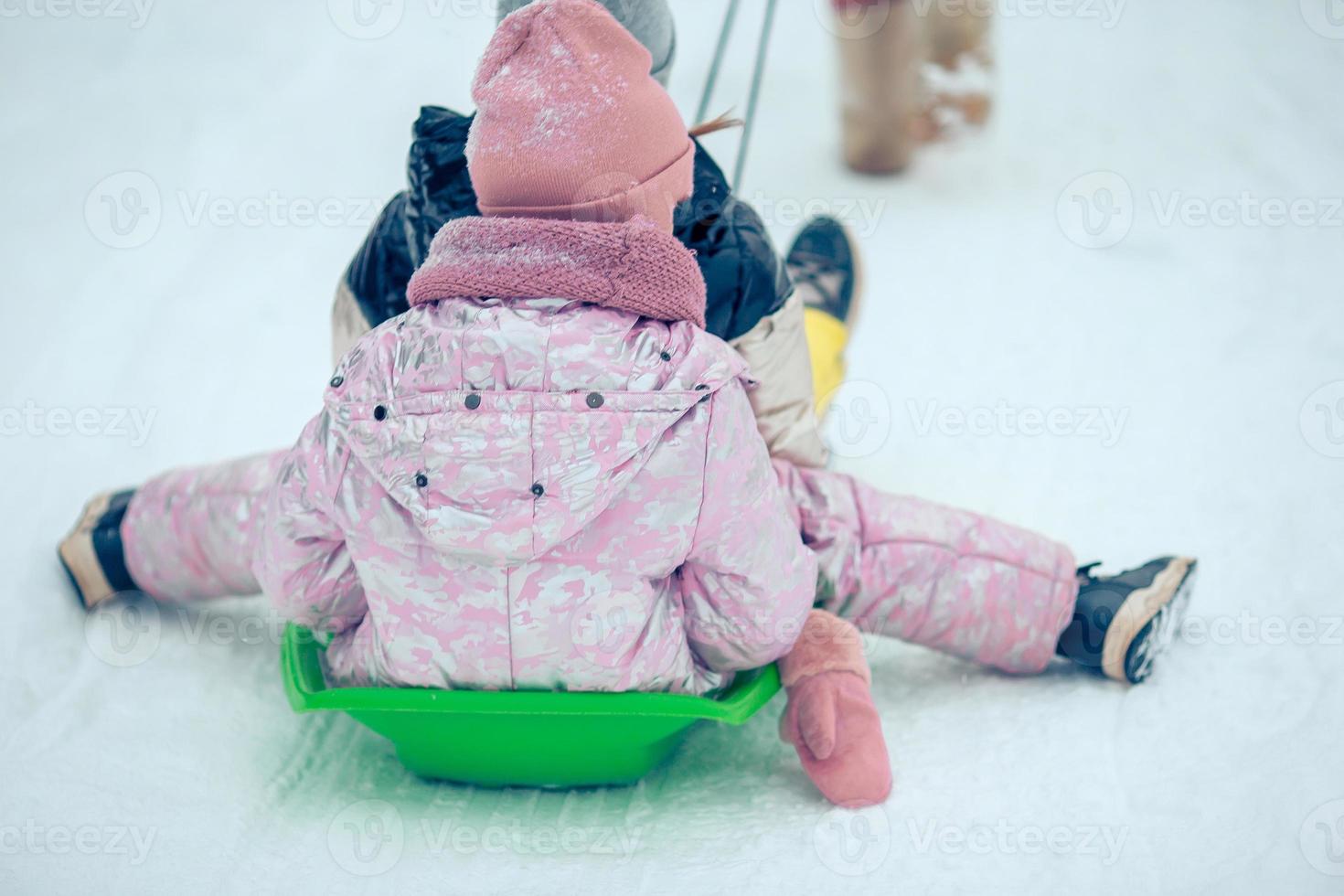 Adorable little happy girls sledding in winter snowy day. photo
