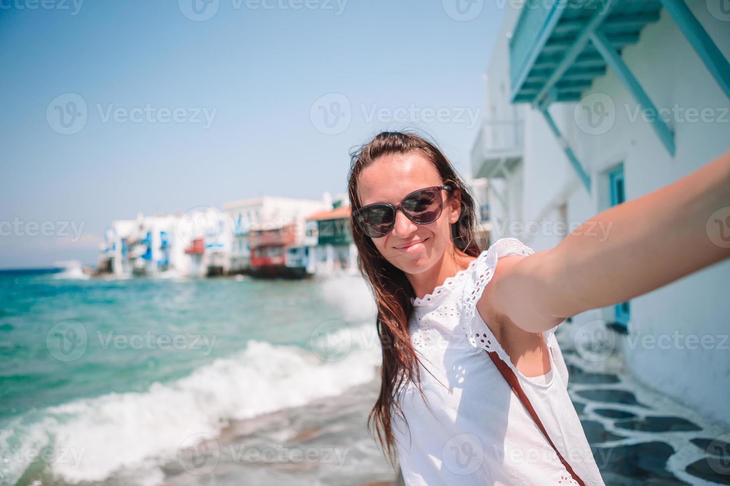 joven hermosa mujer tomando selfie con teléfono al aire libre casa blanca de fondo foto