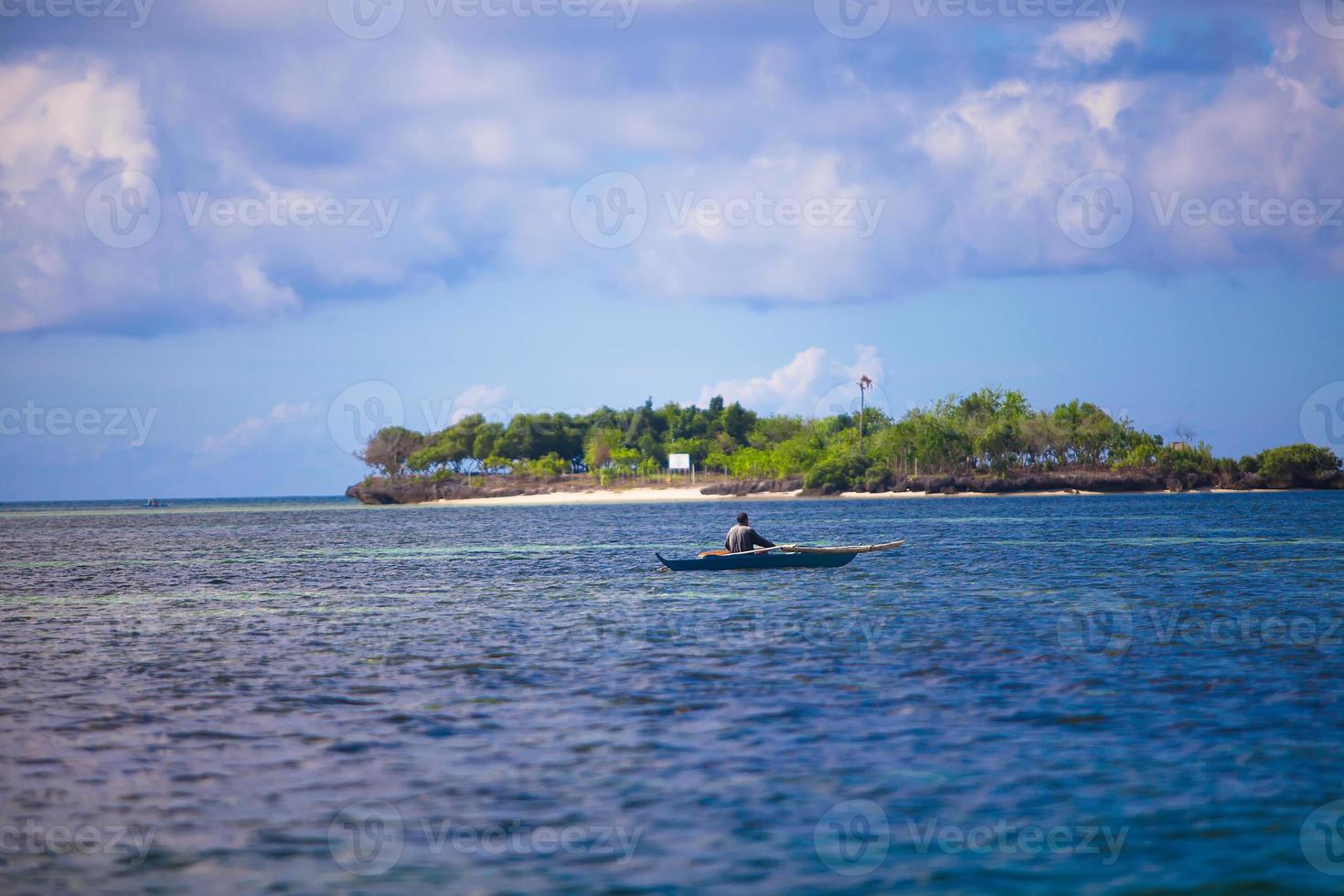 Poor Fisherman in boat at clear blue sea Philippines photo