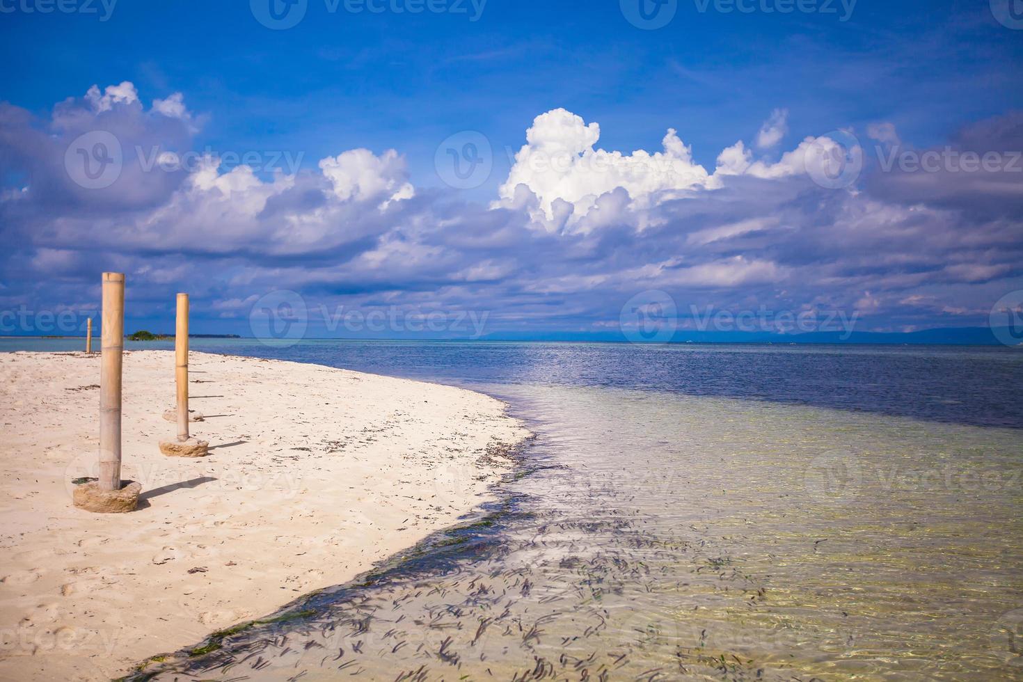 Perfect white beach with turquoise water and a small fence on desert island photo