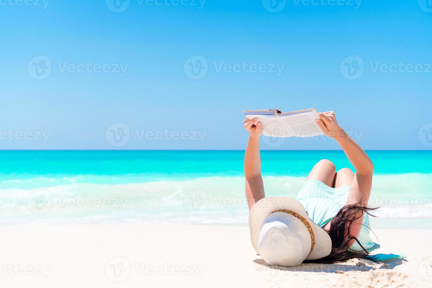 Young woman reading book during tropical white beach photo