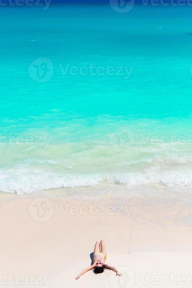 Happy girl at beach in shallow water with small waves. Top view of beautiful girl on the seashore photo
