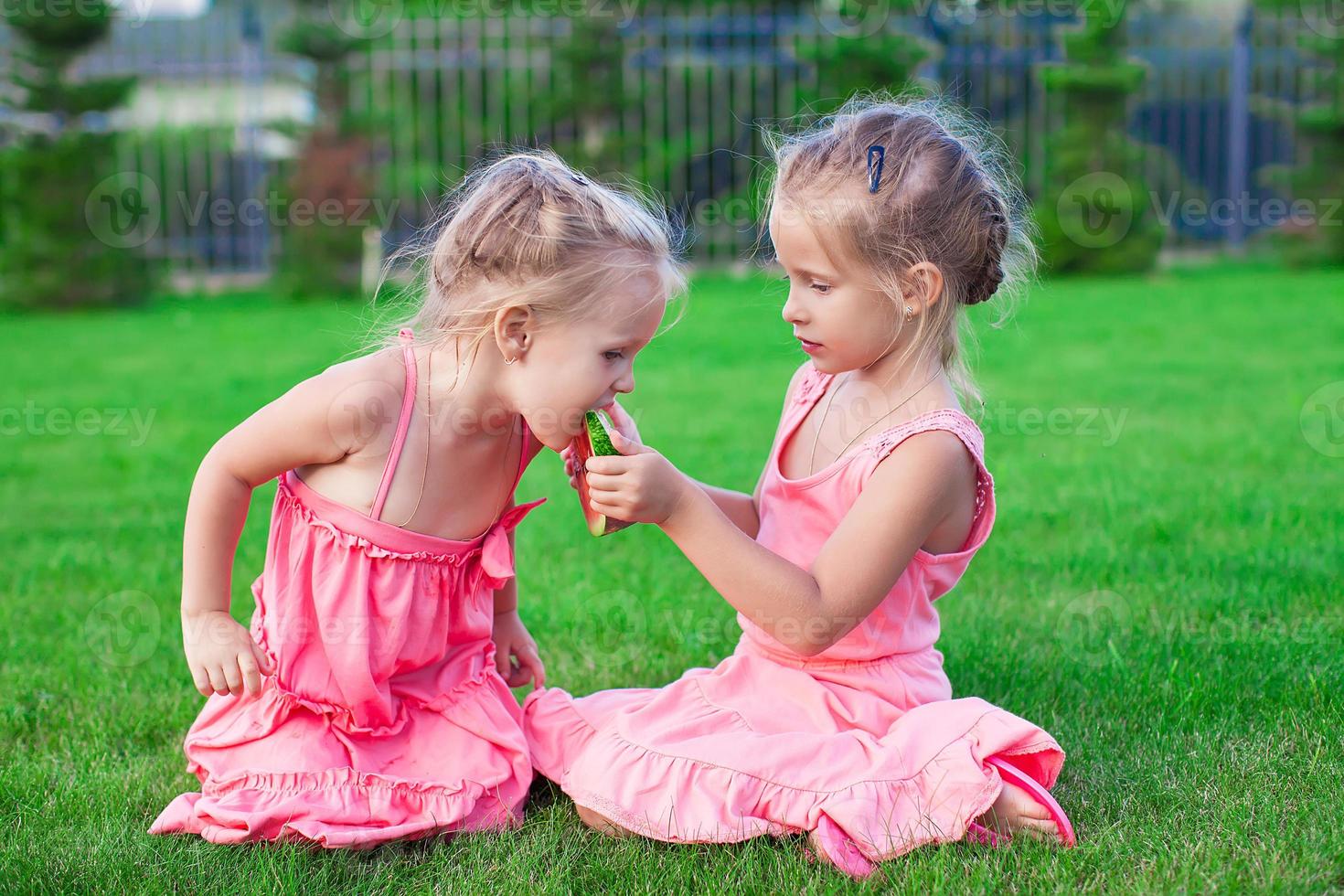 Older sister feeding younger piece of watermelon on a hot summer day photo