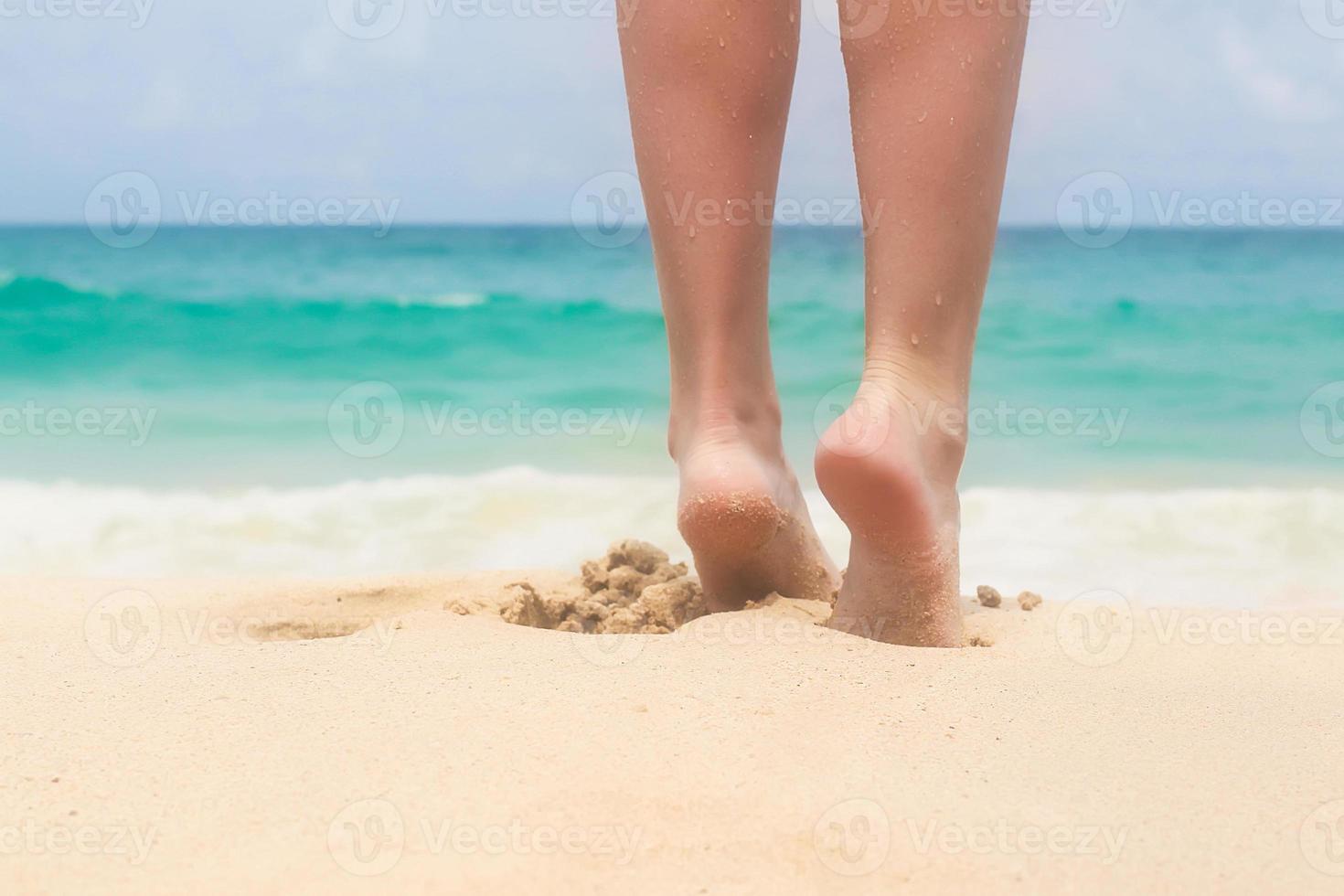 Women's beautiful smooth legs on white sand beach photo