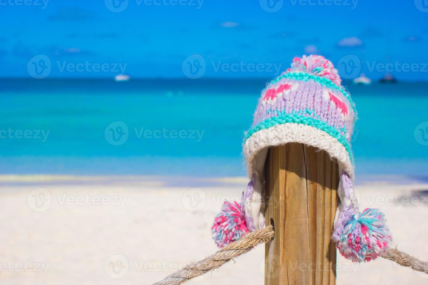 Closeup warm knitted cap on fence at tropical beach photo