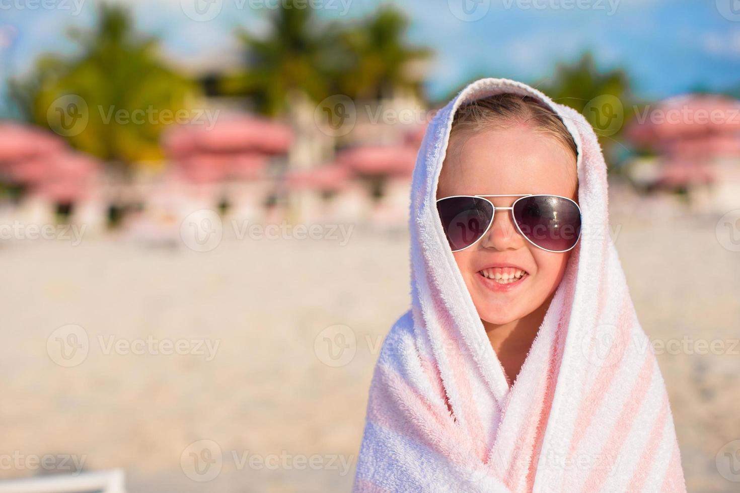 Portrait of little girl covered with towel at tropical beach photo