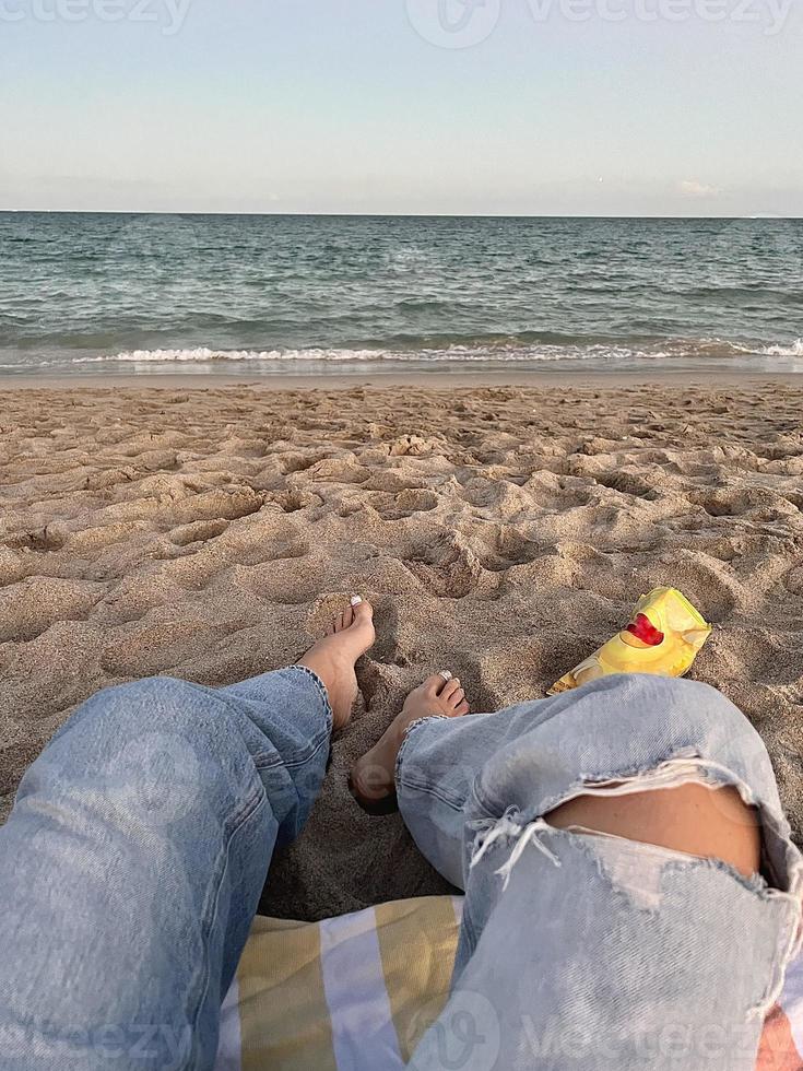 mujer feliz disfrutando de la hermosa puesta de sol en la playa. primer plano de las piernas en la arena foto