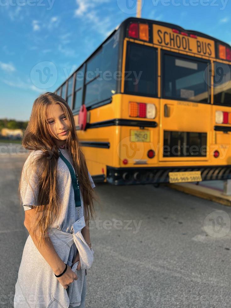 Beautiful teen girl getting on school bus photo
