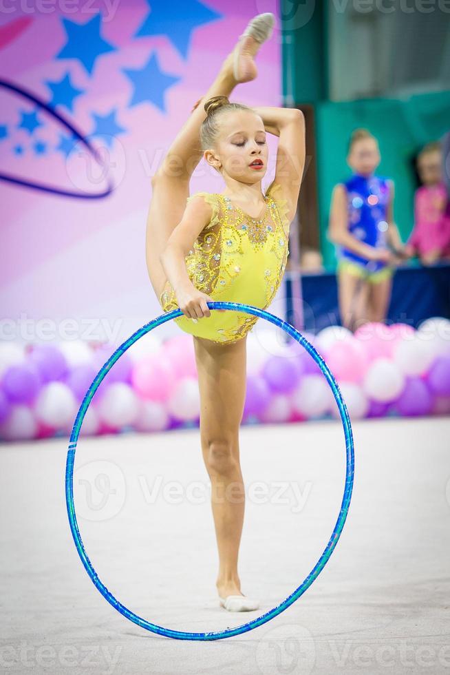 Little gymnast participates in competitions in rhythmic gymnastics photo