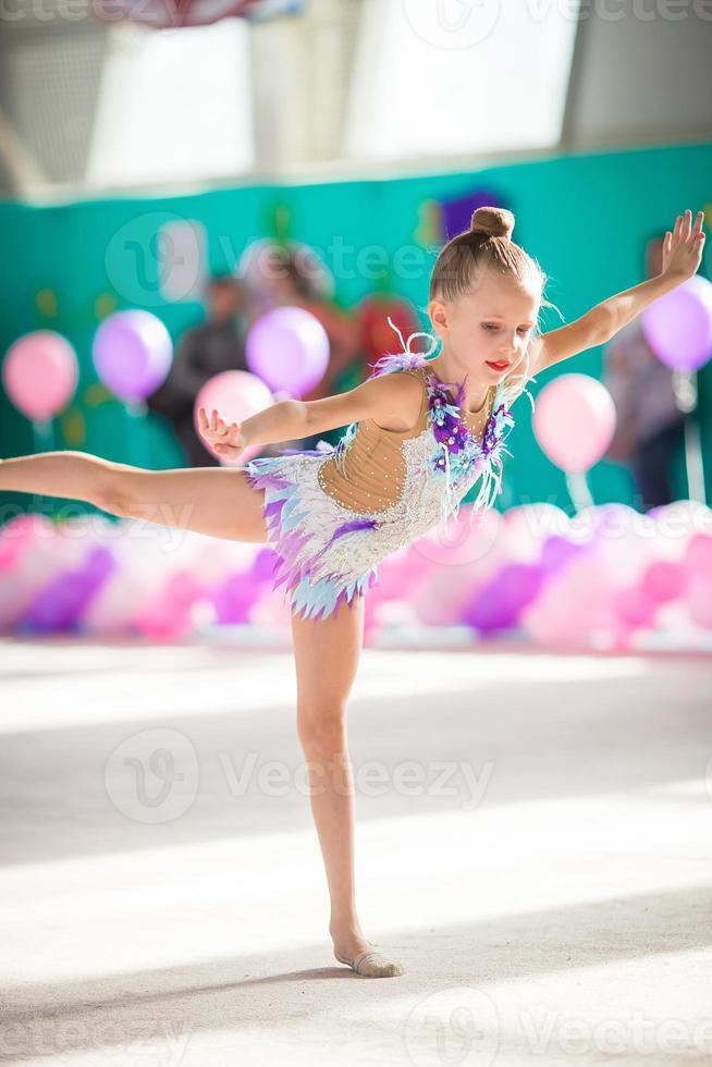 pequeña y hermosa gimnasta en competiciones foto