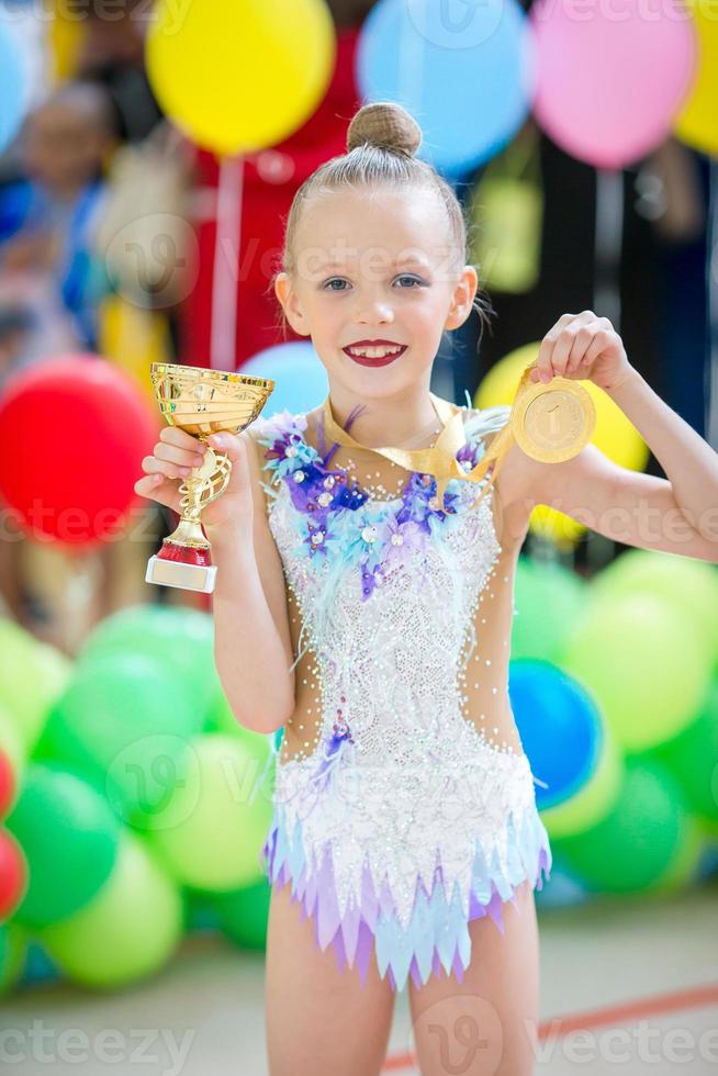 hermosa pequeña gimnasta entrenando en la alfombra y lista para las competiciones foto