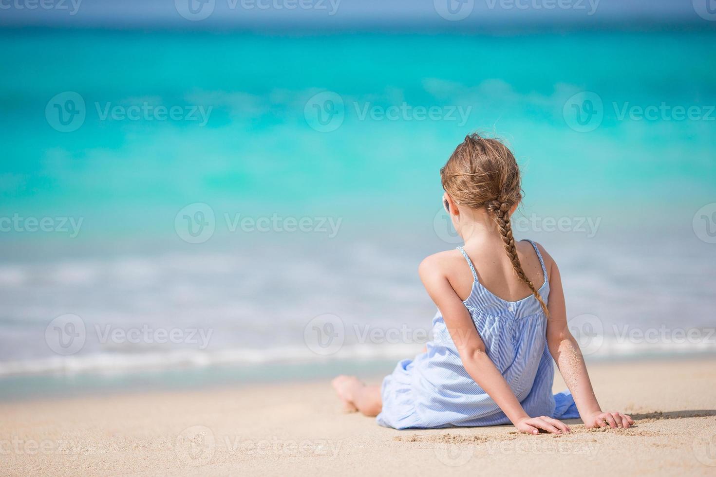 Beautiful little girl in dress at beach having fun. photo