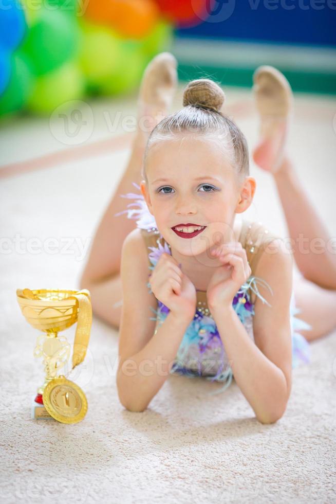 hermosa pequeña gimnasta entrenando en la alfombra y lista para las competiciones foto