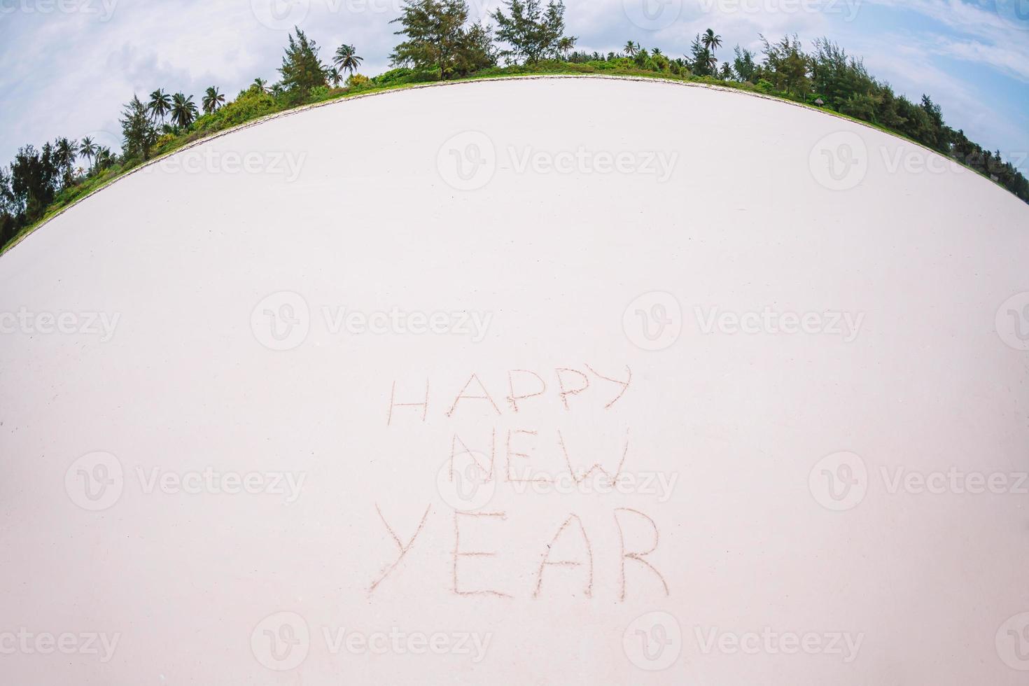 feliz año nuevo escrito en la arena blanca foto