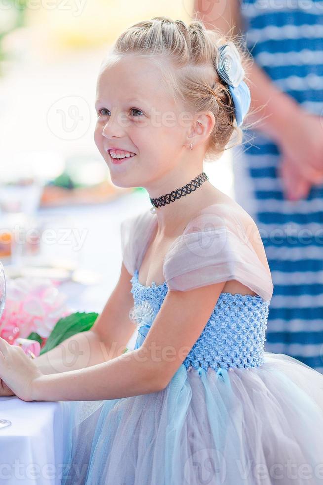 Adorable little girl in amazing dress at a wedding ceremony outdoors photo