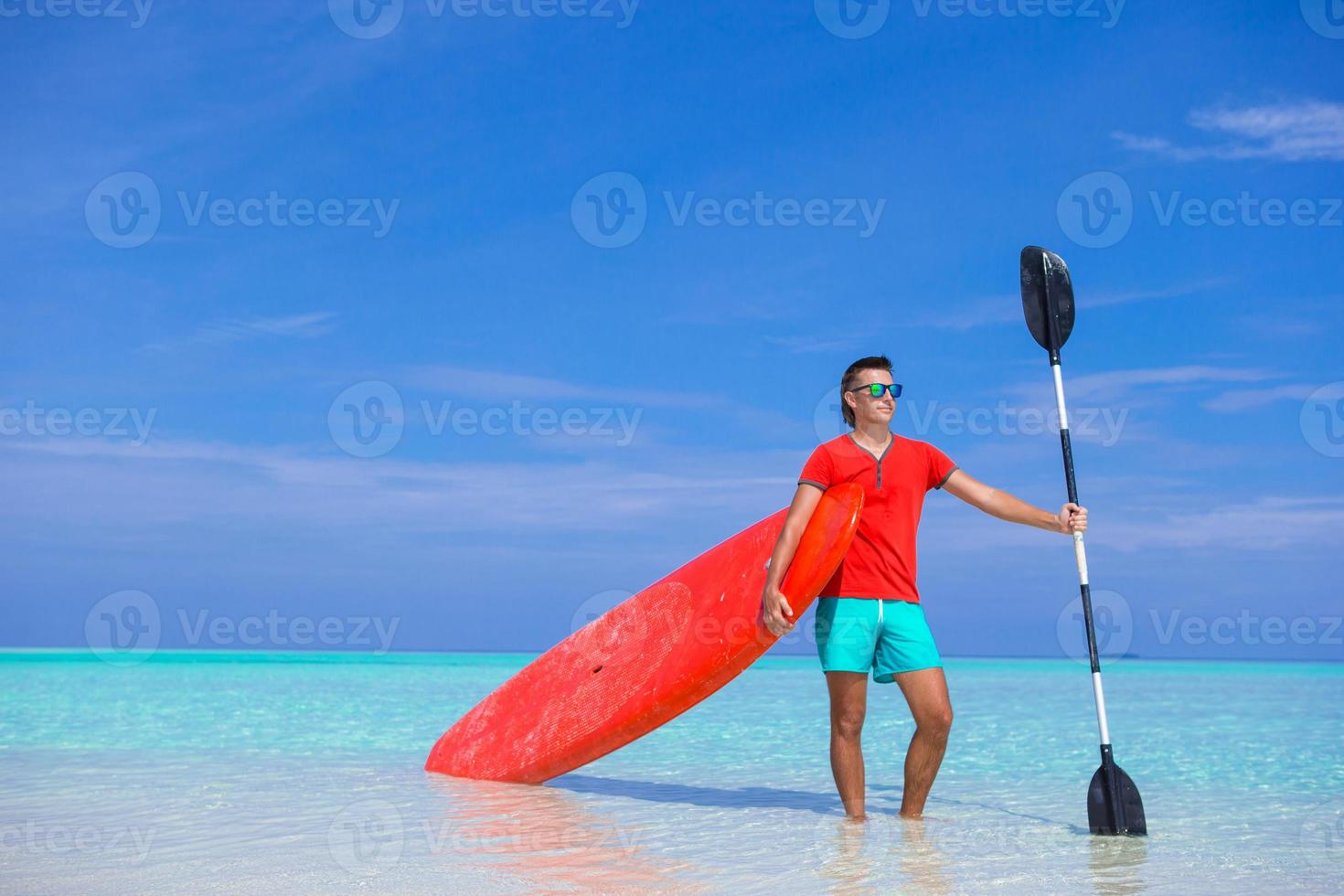 joven feliz con tabla de surf y remo en la costa tropical foto