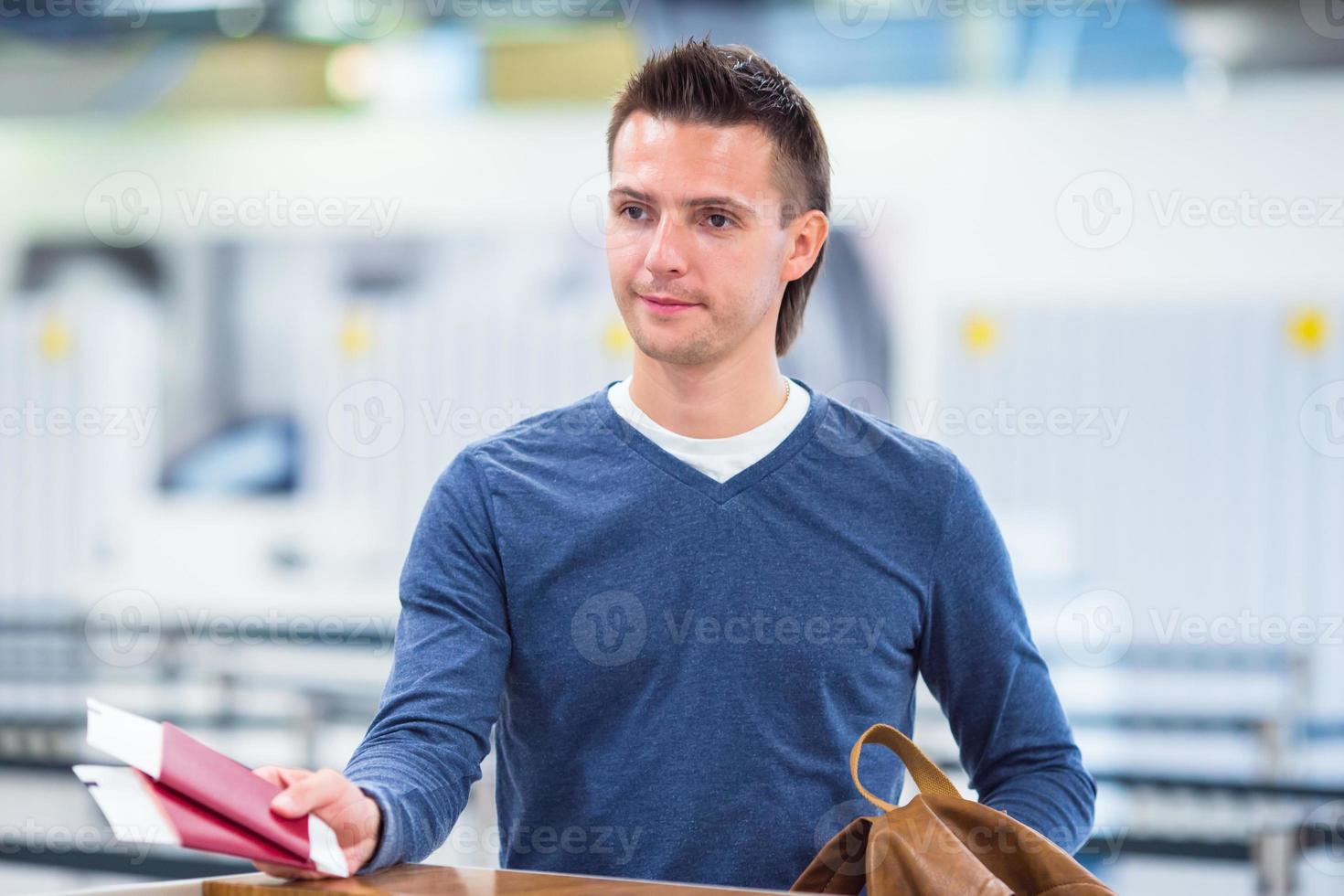 Young man with passports and boarding passes at the front desk in airport photo