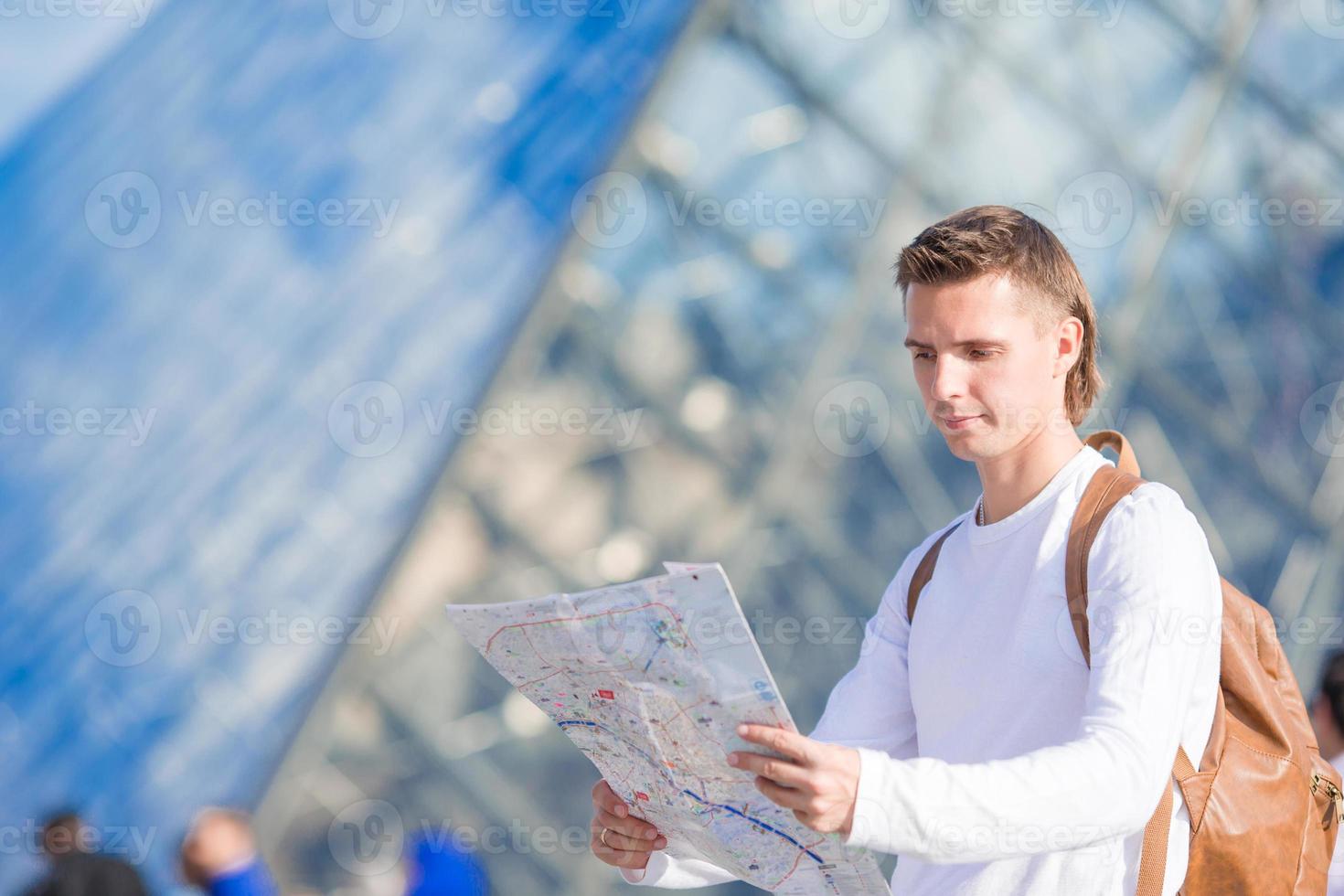Happy young man with a city map in european city outdoors photo