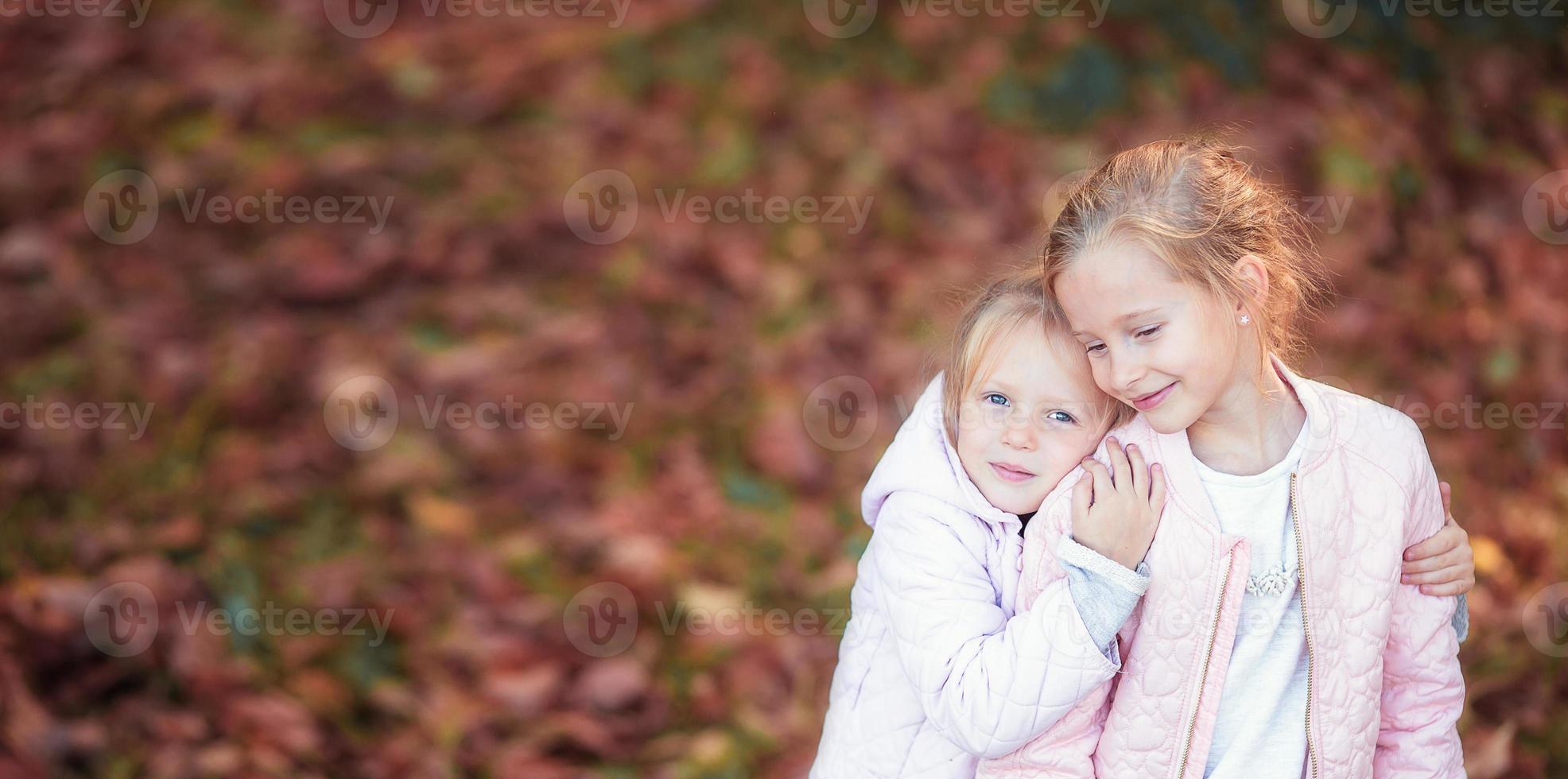 Little adorable kids at warm day in autumn park outdoors photo