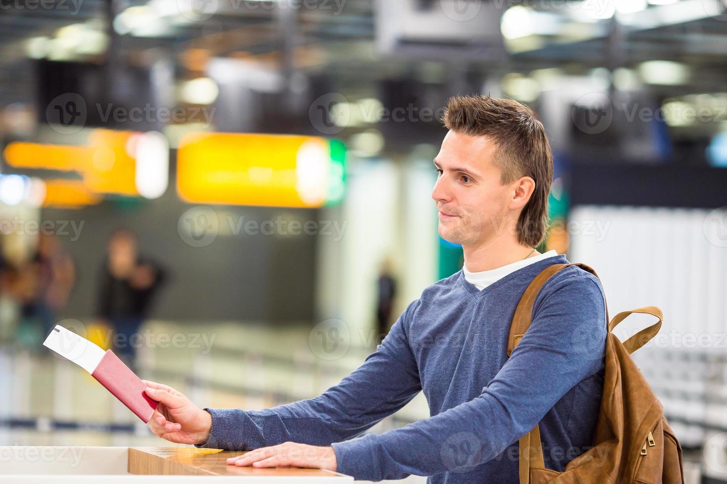 Young man with passports and boarding passes at the front desk in airport photo