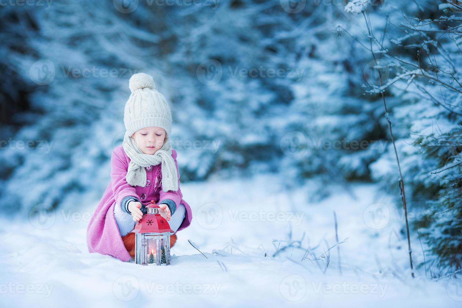 adorable niña con linterna en invierno congelado en navidad al aire libre foto