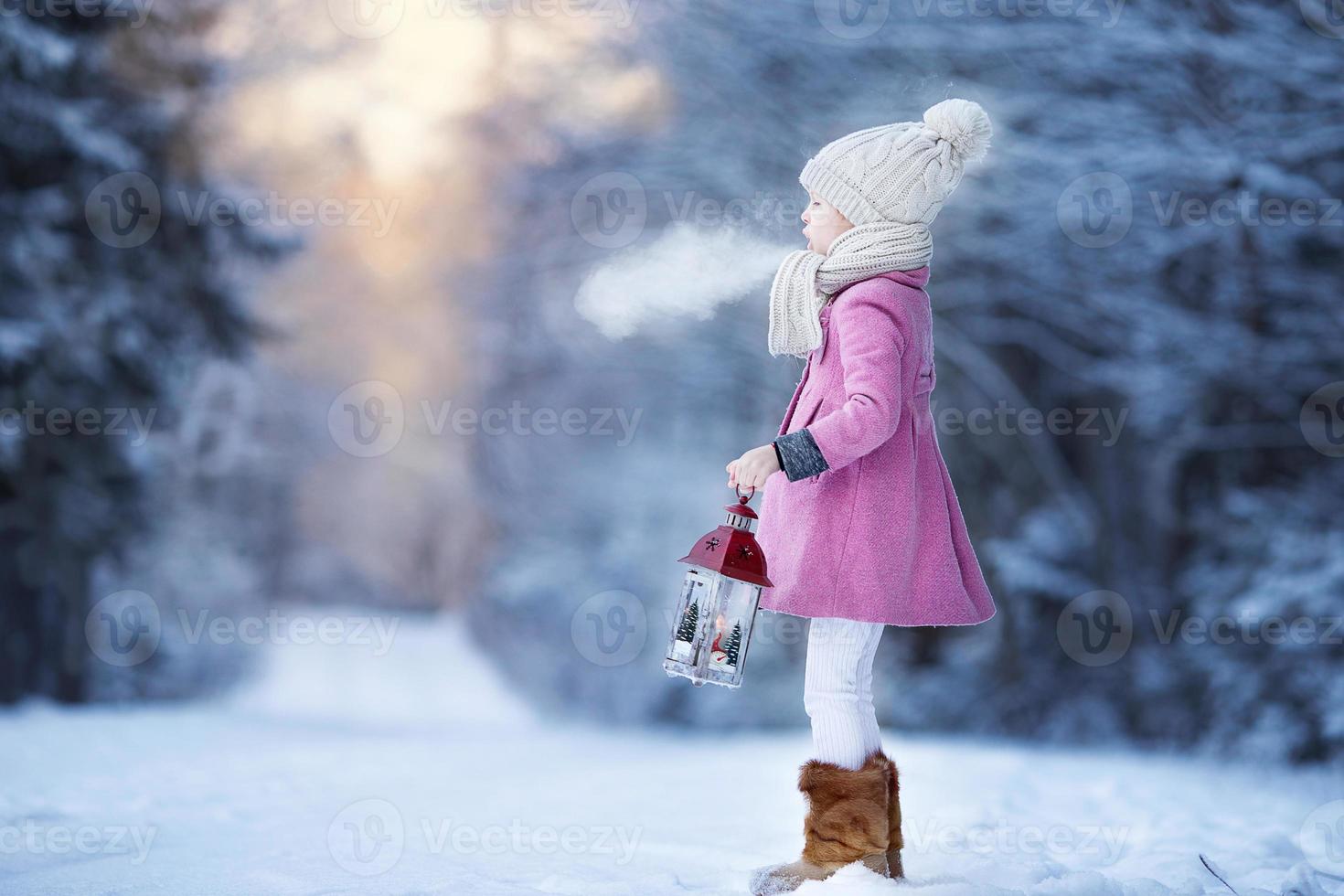 adorable niña con linterna en invierno congelado en navidad al aire libre foto