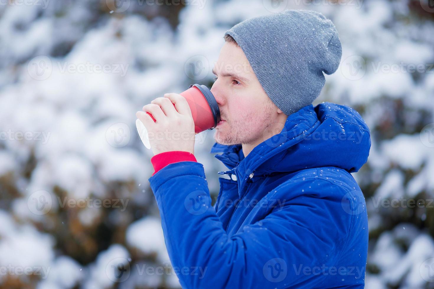 joven caucásico bebiendo café en un día de invierno congelado al aire libre foto