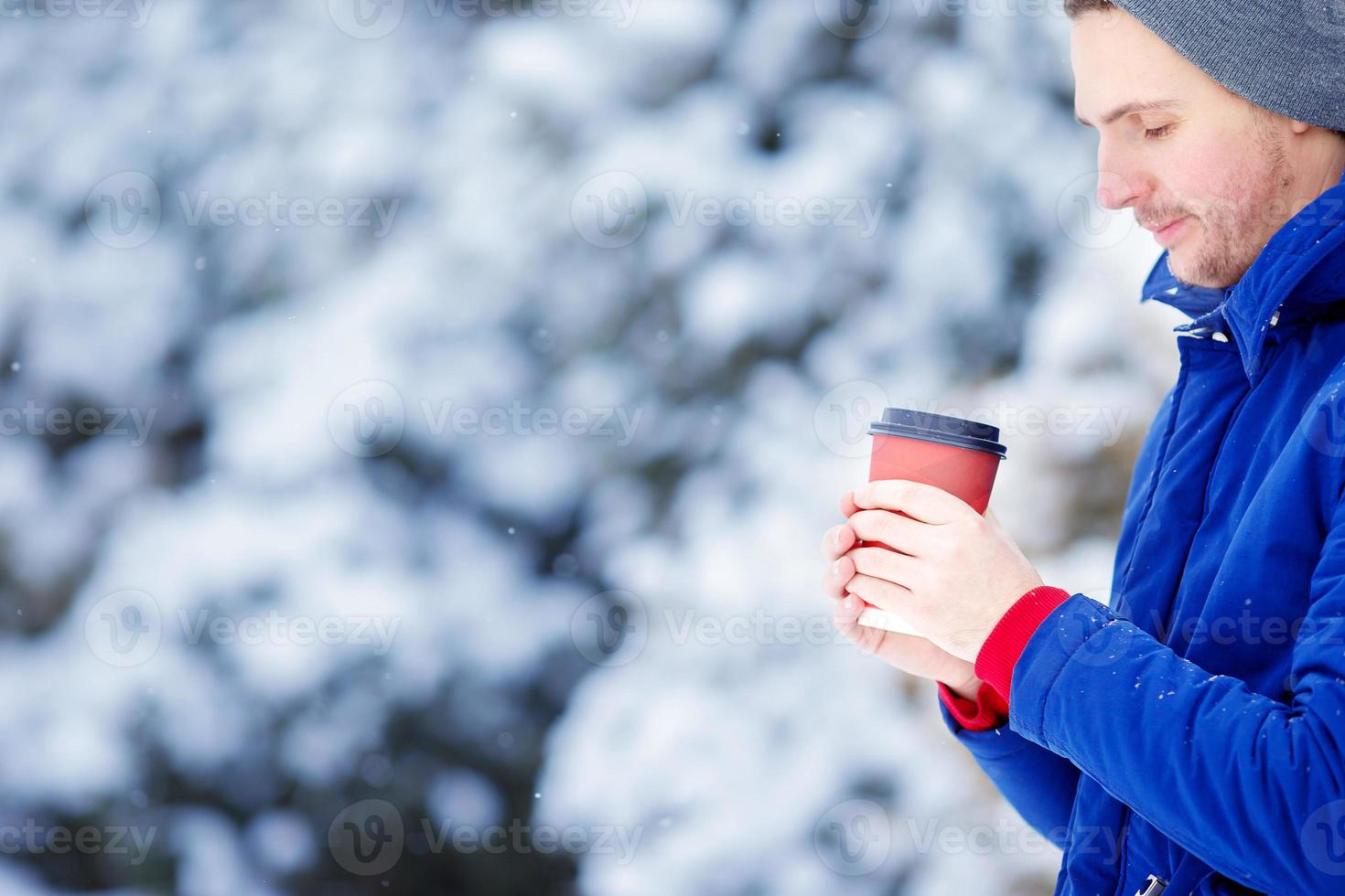 Young caucasian man drinking coffee in frozen winter day outdoors photo