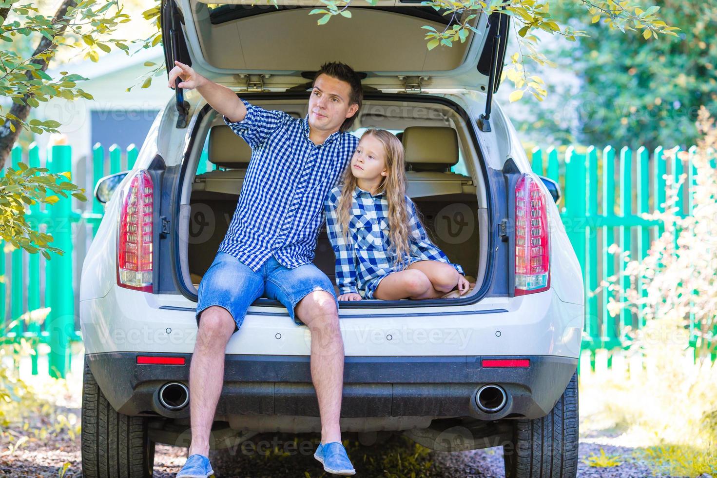 padre con hija sentada en un auto justo antes de irse de vacaciones en auto foto