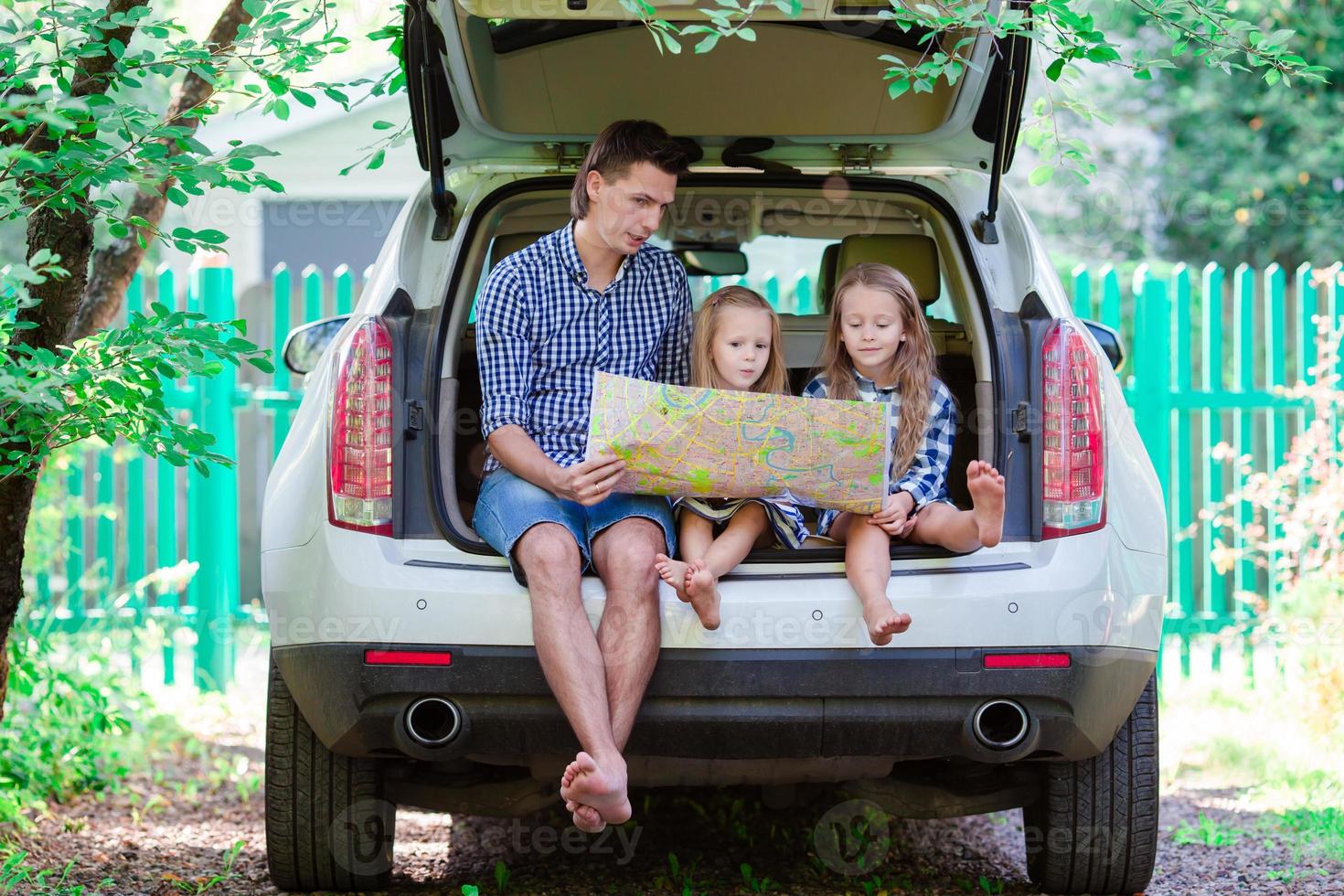 Father with kids looking at map while travel by car photo