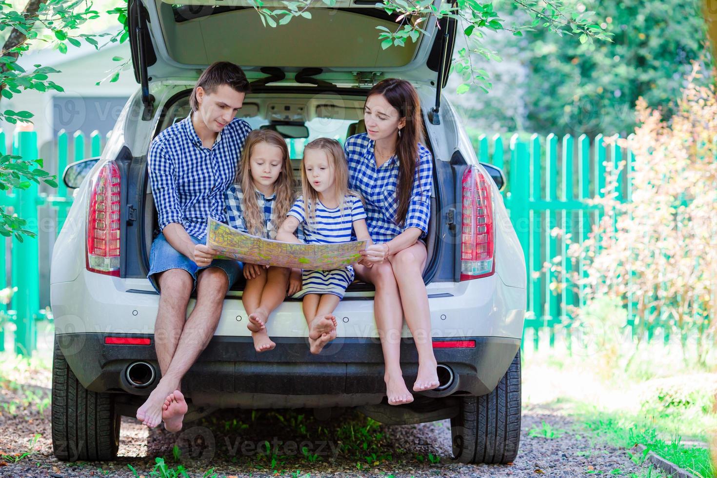 Family with two kids looking at map while traveling by car photo