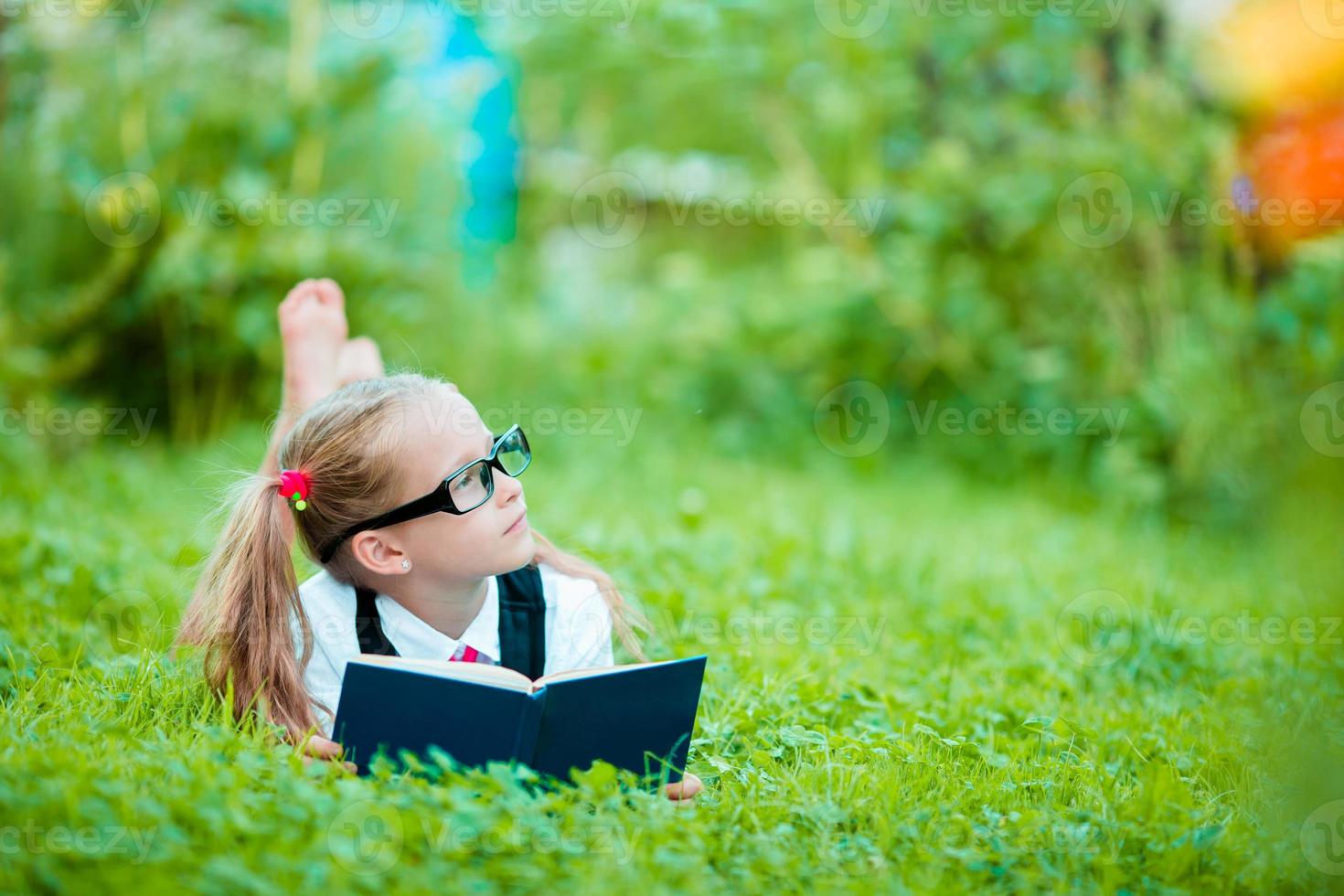 Adorable little girl reading a book outdoors photo