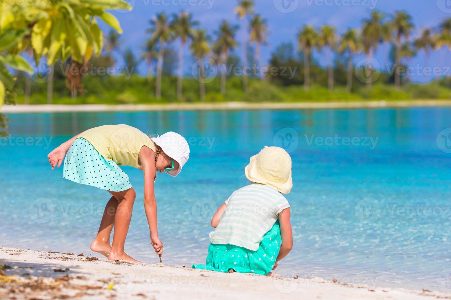 Little adorable girls drawing picture on white beach. Cute kids on summer holidays at Maldives photo