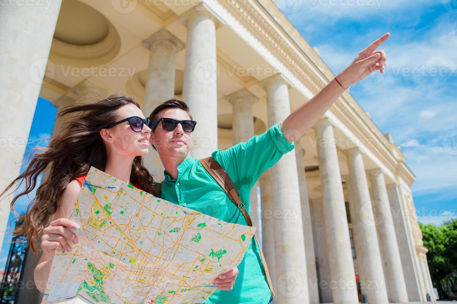 Young tourist friends traveling on holidays in Europe smiling happy. Caucasian family with city map in search of attractions photo