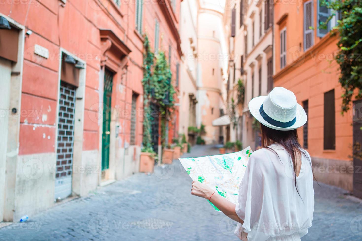 Happy young woman with a city map on desert street in Europe. Travel tourist woman with map in Rome outdoors during holidays in Italy. photo